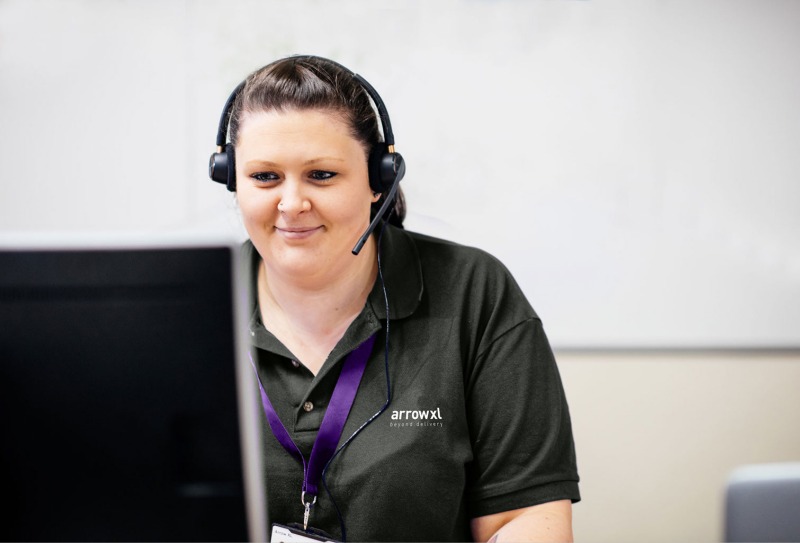 Photograph of an ArrowXL Customer Experience Agent at her desk wearing a headset